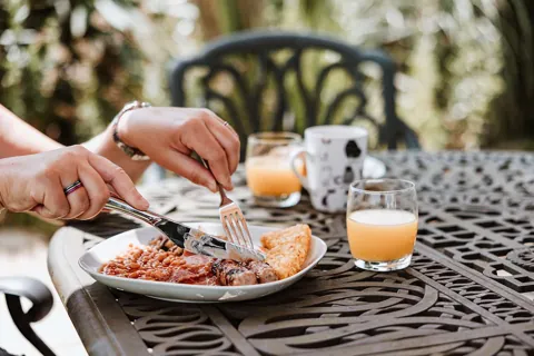 A cooked breakfast and fresh orange juice on the iron garden table