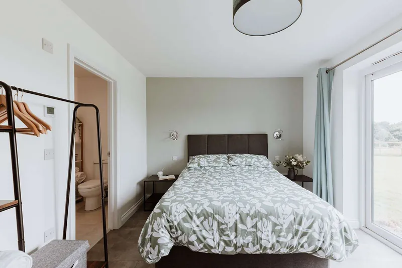 The Gorge Room: king-size bed with soft green bedding, clothes rail and warm lamplight