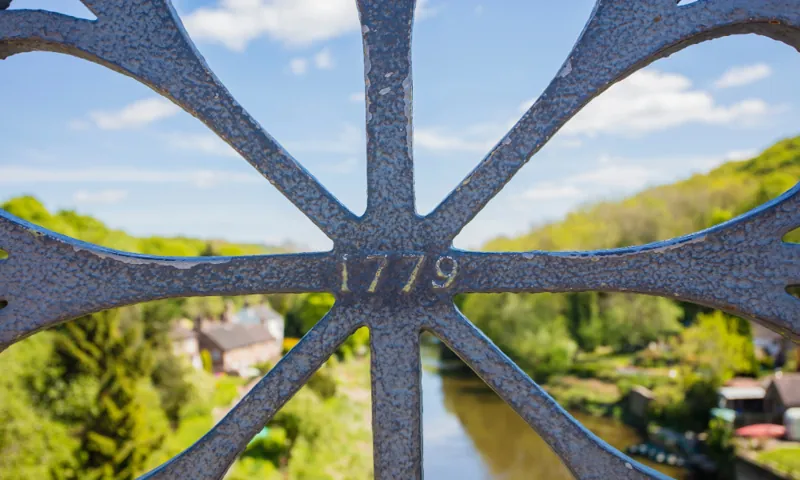 The 1779 date cast into the Iron Bridge's lattice, the gorge glowing green beyond